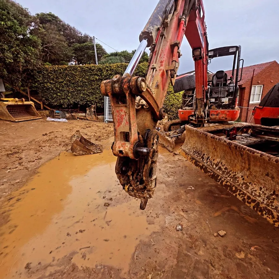 Mini excavator quick hitch on a muddy worksite
